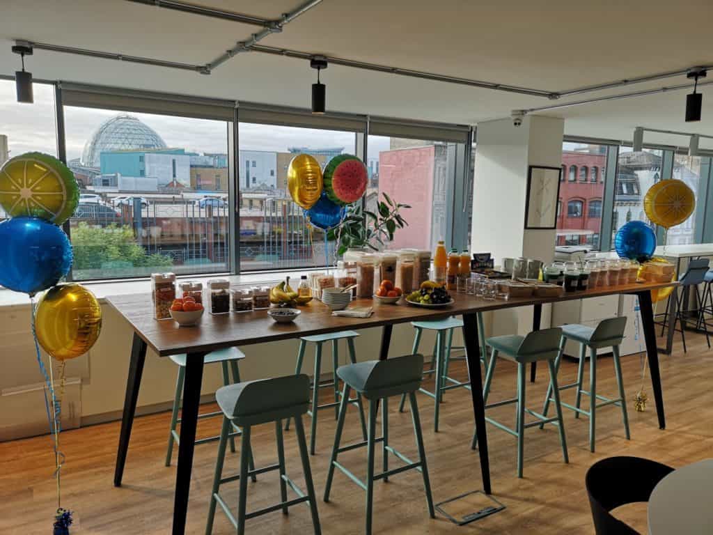 A table of healthy breakfast at Signifyd's Belfast R&D center with the Belfast skyline out the window in the background