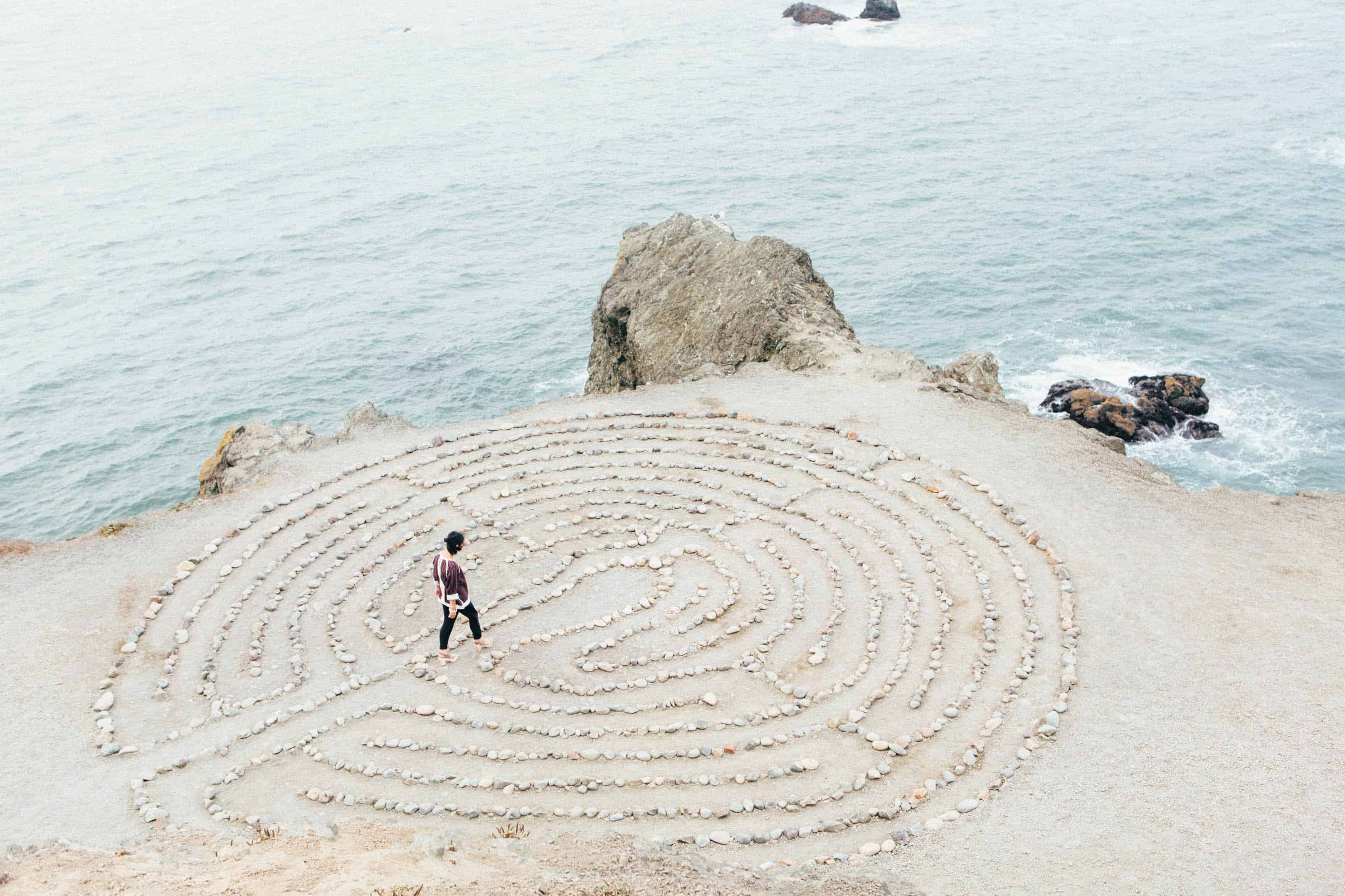 A woman on the ocean's edge walking a labyrinth