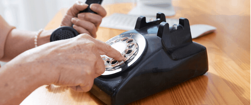 Person dialing a rotary phone to make a telephone order
