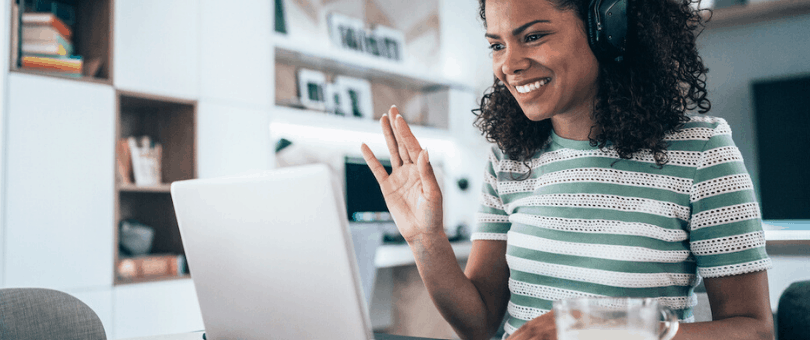 A smiling woman working on a laptop from home to represent Signifyd's dispersed workforce