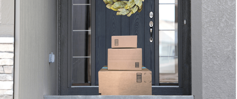 A stack of online sales packages outside a front door decorated with a wreath