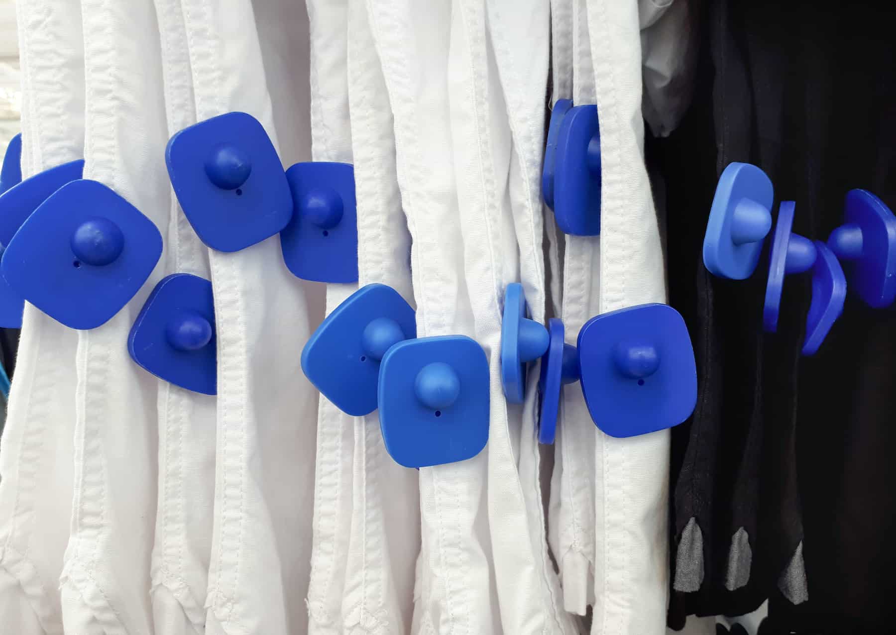 Photo of shirts on a rack with large security RFID tags to discourage shoplifting to illustrate Gartner's Don't Treat your customers like criminals