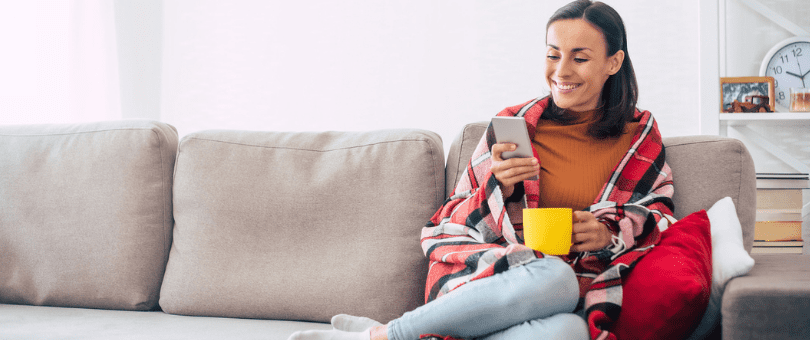 Woman shopping on a coach shopping by phone to represent consumer using PayPal