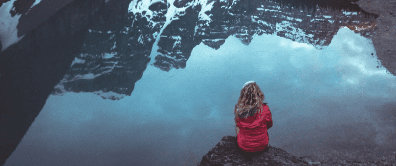 Woman sitting alone at Moraine Lake recharging