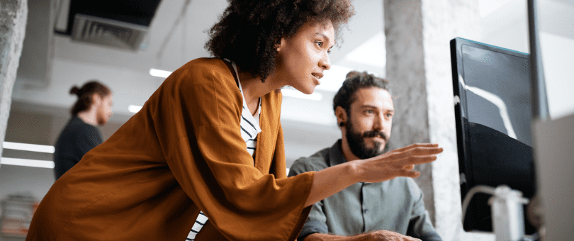 A man and a woman study fraud trends on a large monitor