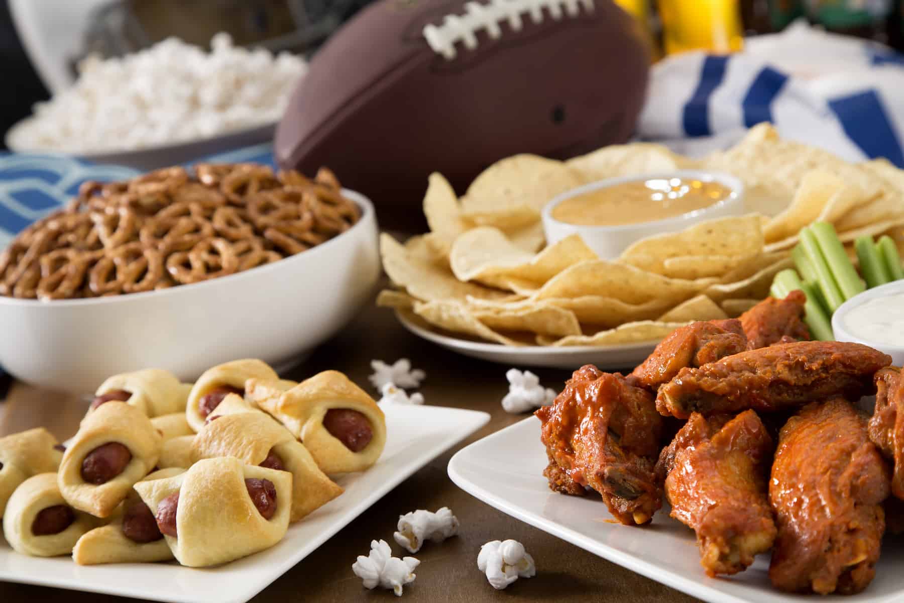 A Super Bowl party spread with pigs in a blanket and chicken wings and tortilla chips and dip