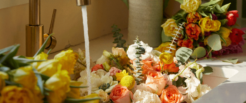 Beautiful cut flowers in a kitchen sink with water splashing down to illustrate the UrbanStems/Signifyd customer story