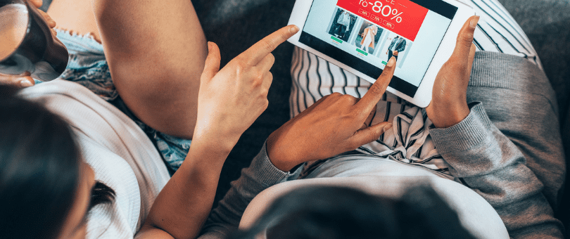 two women shopping online on a tablet at a site offer a deep discount