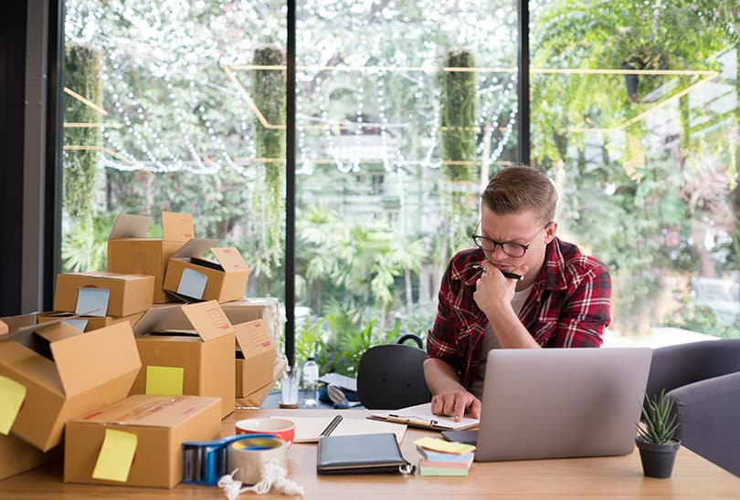 frustrated startup small business owner working at workplace. stressed freelance man seller check product order for delivery. Online selling, e-commerce, shipping concept