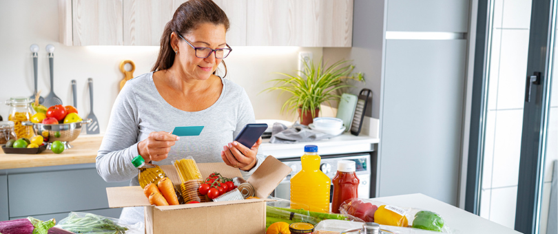 A woman unpacking grocery delivery to illustrate Signifyd August Ecommerce Pulse blog post