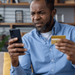 A man, frustrated, with mobile phone and credit card in his hand to illustrate Signifyd false declines blog