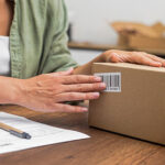 A woman prepares a package containing an ecommerce return for shipping back to the merchant