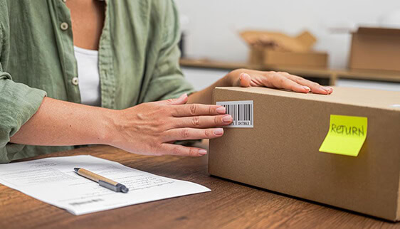 A woman prepares a package containing an ecommerce return for shipping back to the merchant