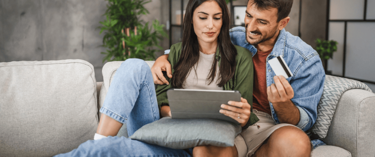 A couple on a couch, shopping online, looking happy for how to improve ecommerce customer experience blog