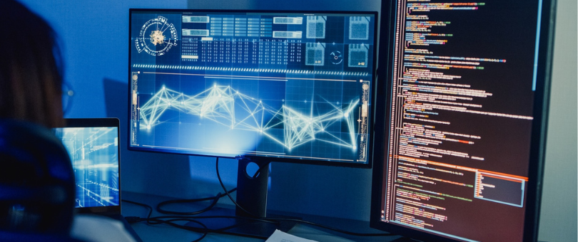 Developer working on Ai algorithms with two monitors in the dark