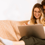 Happy couple on a couch with laptop, shopping on line for ecommerce customer satisfaction post