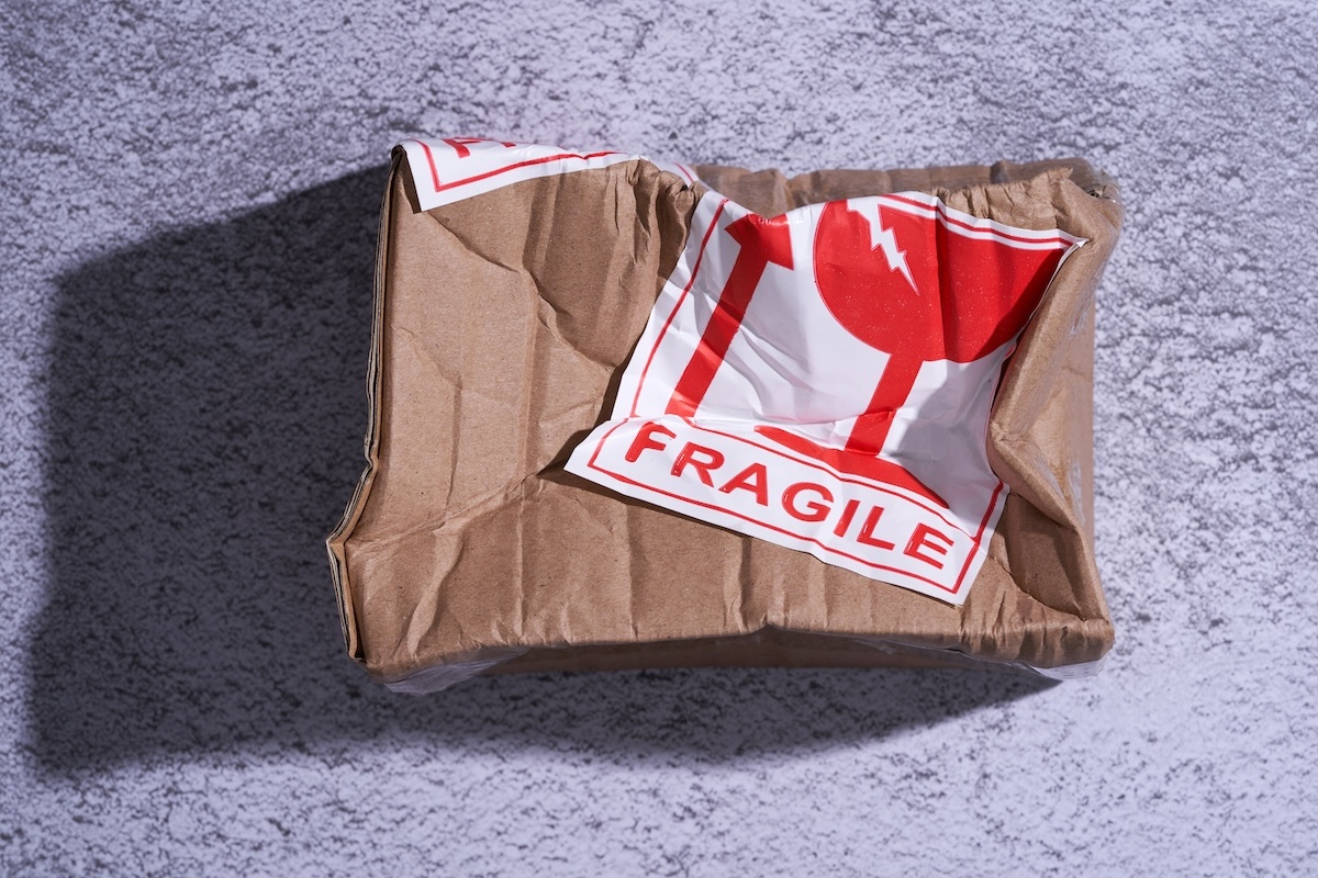 A crushed box labeled "Fragile" symbolizing post-purchase dissonance