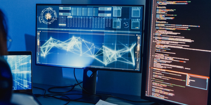 Developer working on Ai algorithms with two monitors in the dark