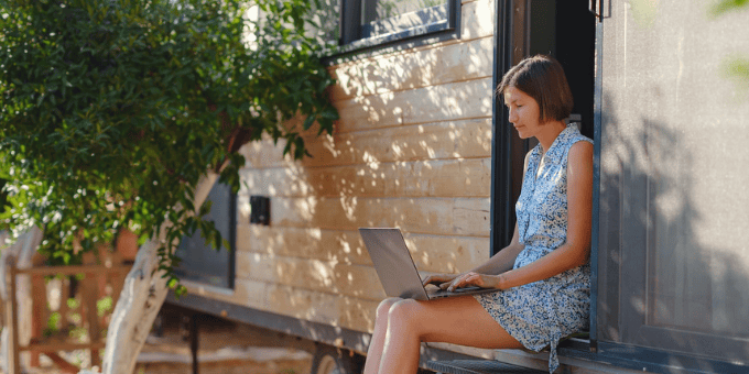 A woman sitting in a warm backyard shopping on a laptop for holiday predictions post