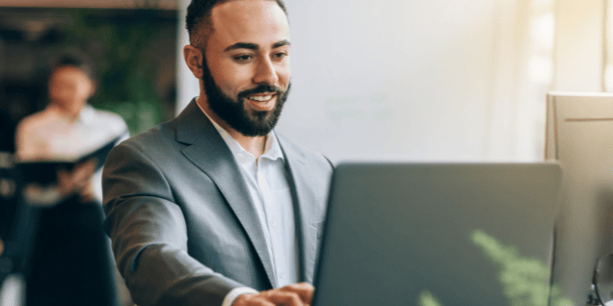 A male business analyst looking pleased with results on a laptop