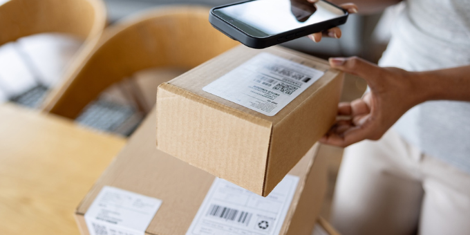 Photo of a woman scanning an ecommerce package with a phone, preparing to return the item