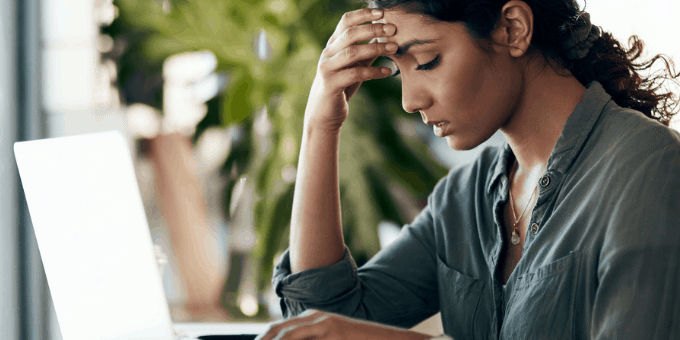 Woman at laptop, hand on forehead, frustrated shopping