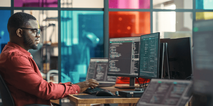 A man working with multiple screens, in the pursuit of ecommerce fraud protection