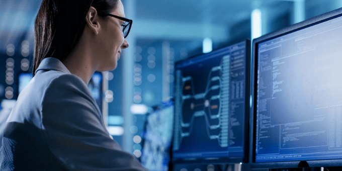 A data analyst at a set of two monitors to illustrate chargeback investigations