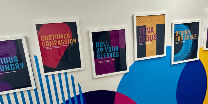 Signifyd's wall of values, a colorful wall — brand colors — with framed values messages spanning a corridor
