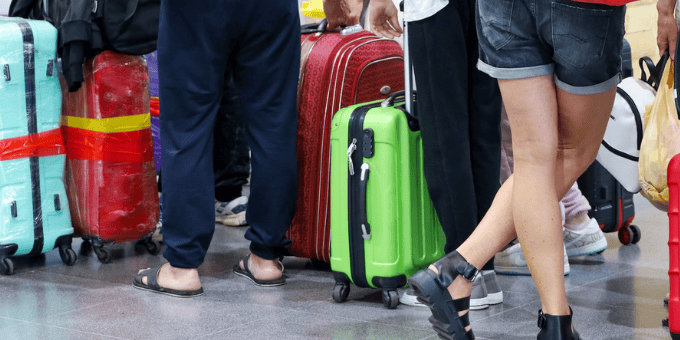 passengers with suitcases lined up in a busy airport to illustrate Signfyd Jeff Wixted's mission to move into airline vertical