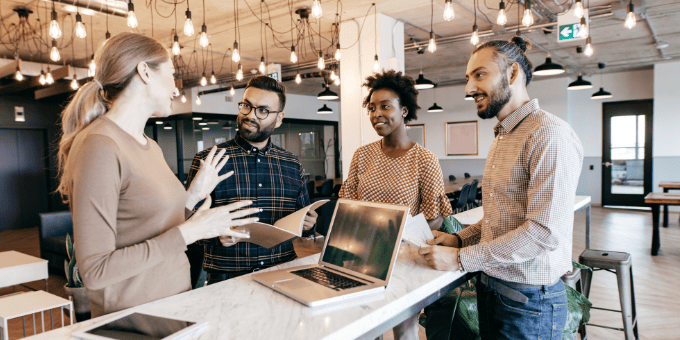Retail-specific fraud experts conferring around a laptop in a modern office.