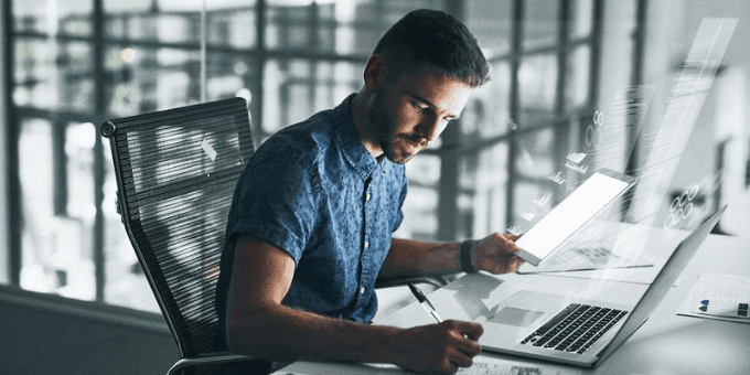 man writing code in a modern glass-filled office
