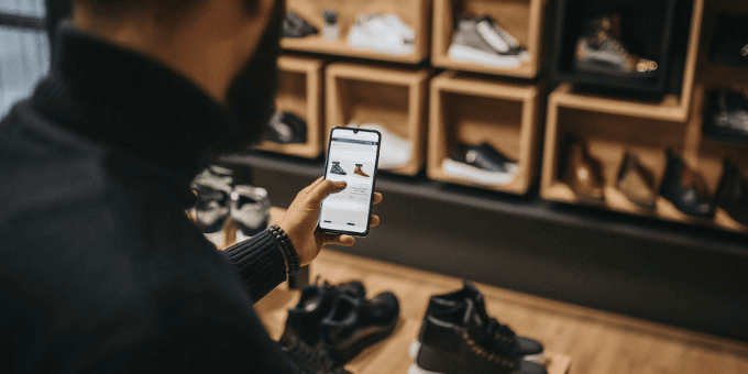 Man shopping for shoes, doing price comparison on his phone