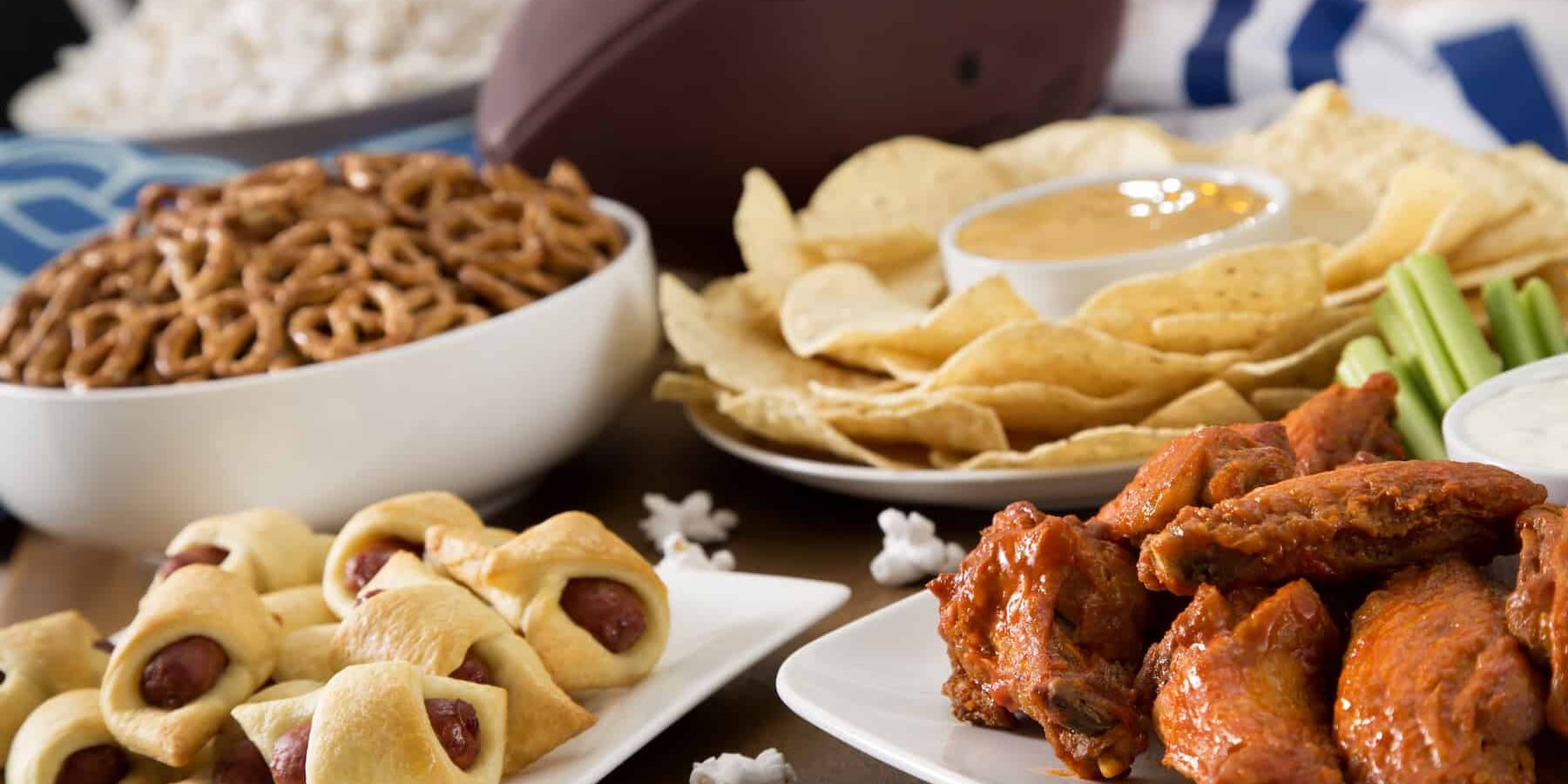 A Super Bowl party spread with pigs in a blanket and chicken wings and tortilla chips and dip