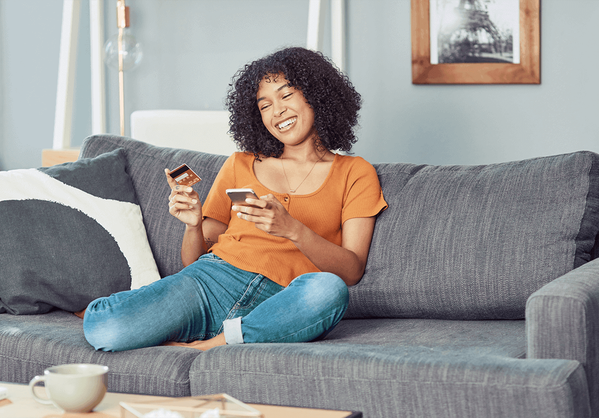woman-buying-online-with-credit-card-in-couch-smiling-1